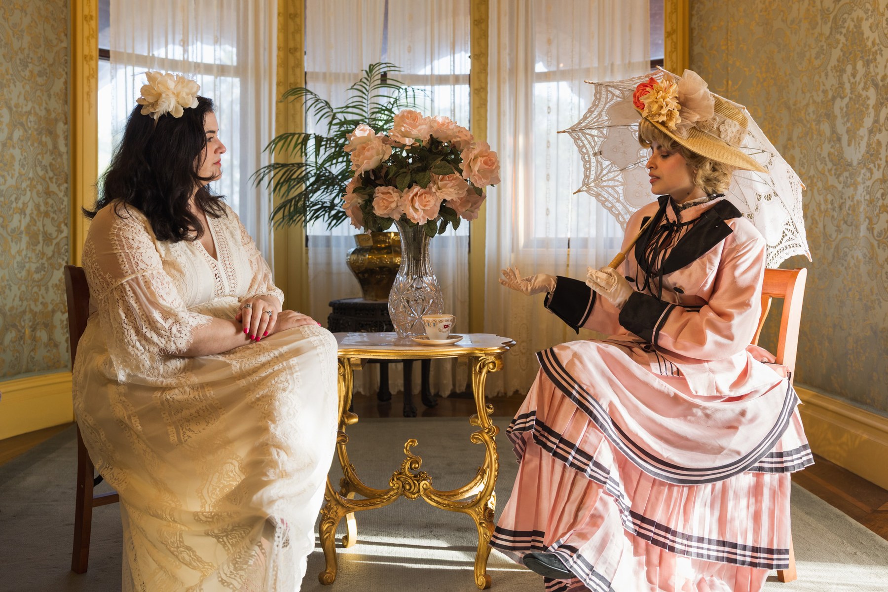 Two guests in Edwardian dress taking afternoon tea